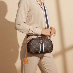 Gabriella G Firenze Valencia skuldertaske i m�rkebrun med G-m�nster, guldfarvet logo og bred stribet skulderrem, b�ret som crossover til beige outfit
