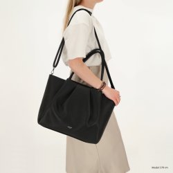 Kvinde med Charm London Lyon sort businessbag b�ret over skulderen med den lange rem, som viser taskens st�rrelse og pasform.