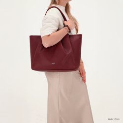 Kvinde med Charm London Lyon bordeaux shopper over skulderen, der viser taskens st�rrelse og elegante facon.