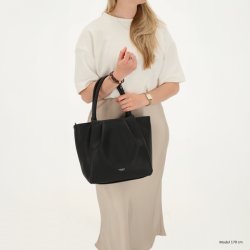 Kvinde i lys nederdel med Charm London Lyon sort shopper b�ret i de lange hanke, som viser taskens st�rrelse og elegante facon.